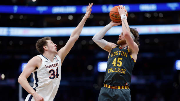 A Virginia men's basketball player contests the shot of a Boston College player