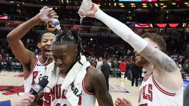 Chicago Bulls guard Ayo Dosunmu (center) is doused with water by forward Dalen Terry (left) and forward Onuralp Bitim (right)