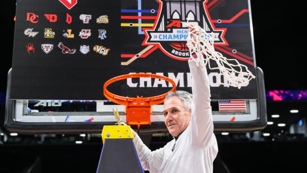 Duquesne coach Keith Dambrot holds the basketball net after the team won the A-10 Conference title.