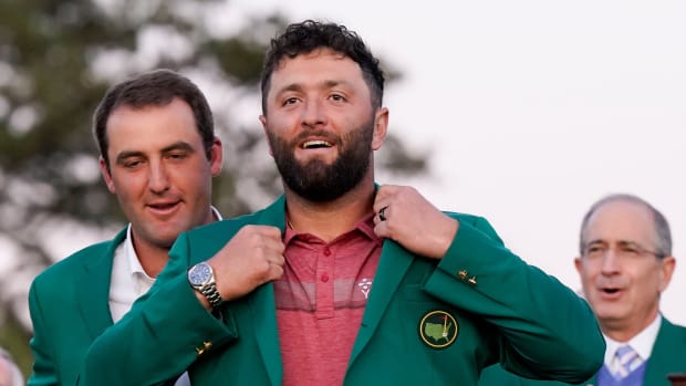 2022 Masters champion Scottie Scheffler helps Jon Rahm into his green jacket after the final round of The Masters golf tournament.