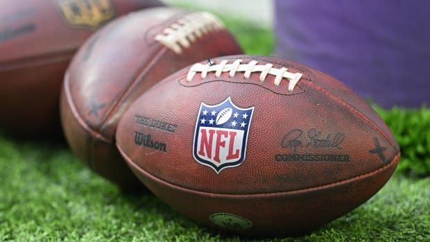Three footballs sit on a field before a game.