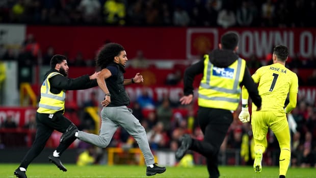 Security staff at Old Trafford pictured trying to catch a pitch invader during a Premier League game between Manchester United and Wolves in August 2023
