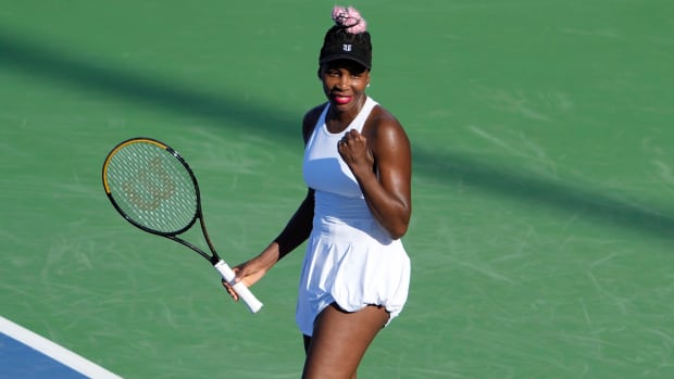 Venus Williams bends her arm with her fist up in celebration, holding her racket in the other hand