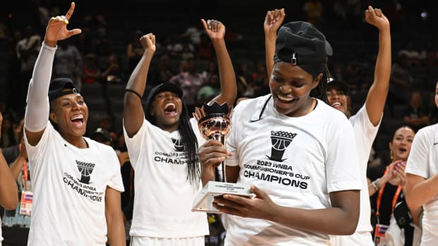 New York Liberty forward Jonquel Jones smiles after being named the MVP of the Commissioner's Cup with teammates cheering behind her.