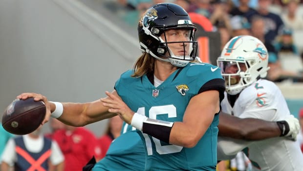 Trevor Lawrence throws the ball as a Dolphins defender is blocked by his O-line