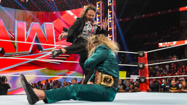 Shinsuke Nakamura delivers a kick to a seated Seth Rollins