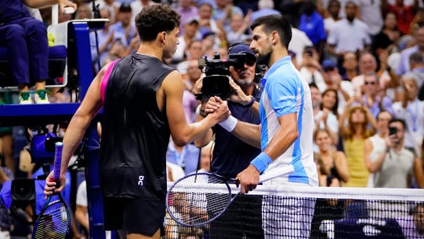 Tennis player Novak Djokovic shakes hands with Ben Shelton after winning a match during the U.S. Open.