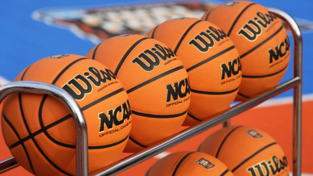 A set of basketballs sit on a rack.