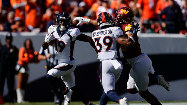 Denver Broncos wide receiver Marvin Mims Jr. (19) runs the football on a punt as running back Dwayne Washington (39) defends against Washington Commanders tight end Cole Turner (85) in the second quarter at Empower Field at Mile High.