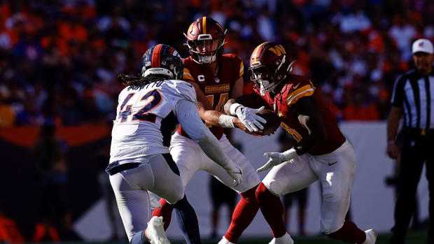 Washington Commanders quarterback Sam Howell (14) hands the ball off to running back Brian Robinson Jr. (8) as Denver Broncos linebacker Nik Bonitto (42) rushes in the third quarter at Empower Field at Mile High.