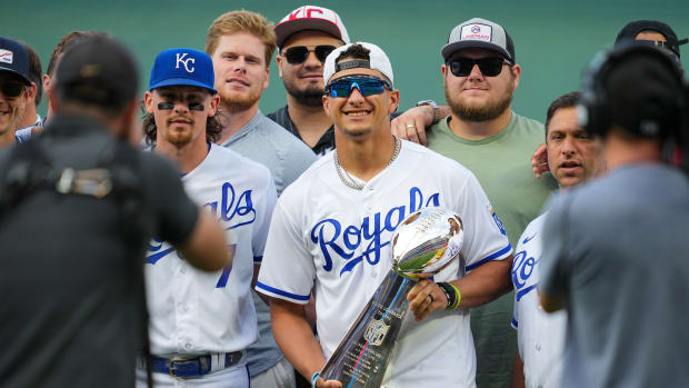 Chiefs quarterback Patrick Mahomes holds up the Lombardi Trophy while wearing a Royals jersey.