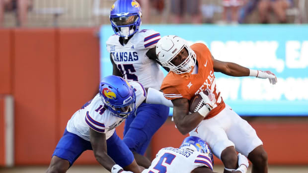 Texas Longhorns defensive back Jahdae Barron is tackled by Kansas Jayhawks safety Jalen Dye, left, and safety O.J. Burroughs in the second half at Royal-Memorial Stadium on Saturday September 30, 2023.  