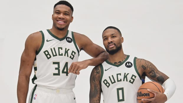 Giannis Antetokounmpo stands with his elbow propped up on Damian Lillard’s shoulder
