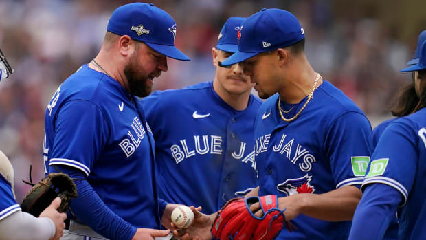 Blue Jays manager John Schneider, left, takes the ball from pitcher Jose Berrios during a pitching change in Game 2 of the AL wild-card series