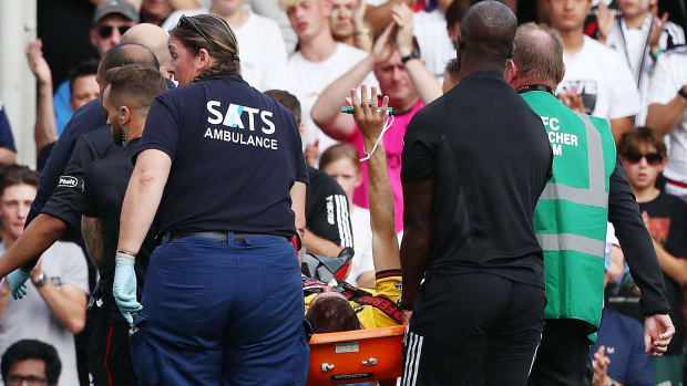 Sheffield United player Chris Basham pictured (center) raising his right arm as he is removed from the field on a stretcher after breaking his left ankle during an EPL game against Fulham in October 2023