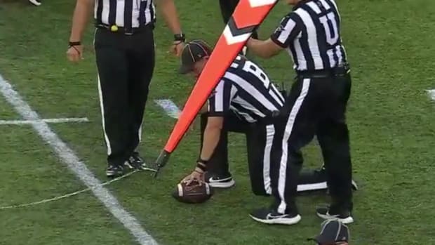 NCAA officials determine a first down after measuring the distance during a college football game.