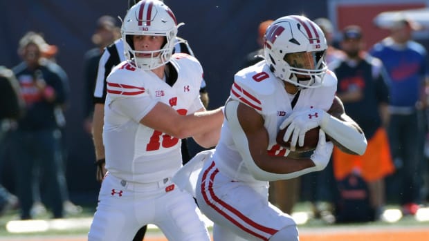 Oct 21, 2023; Champaign, Illinois, USA; Wisconsin Badgers quarterback Braedyn Locke (18) hands the ball to running back Braelon Allen (0) against the Illinois Fighting Illini during the first half at Memorial Stadium. Mandatory Credit: Ron Johnson-USA TODAY Sports