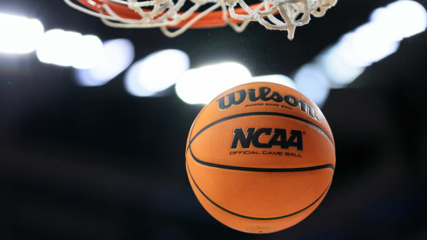 An NCAA basketball goes through a hoop.