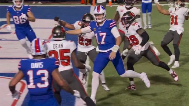 Buffalo Bills quarterback Josh Allen stares down Buccaneers CB Jamel Dean while scoring a rushing touchdown.