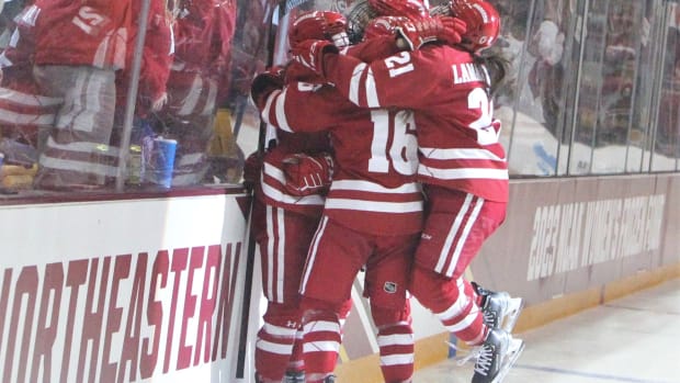 Wisconsin's Nicole LaMantia (21) and Claire Enright (16) are among the players who are part of a group hug after Kirsten Simms scored during the first period of the NCAA Division I women's hockey final Sunday March 19, 2023 at AMSOI: Arena in Duluth, Minn. Uwice Ohio State 8 March 19 2023