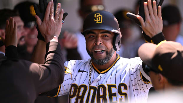 Padres designated hitter Nelson Cruz high fives his teammates in a dugout during a game.