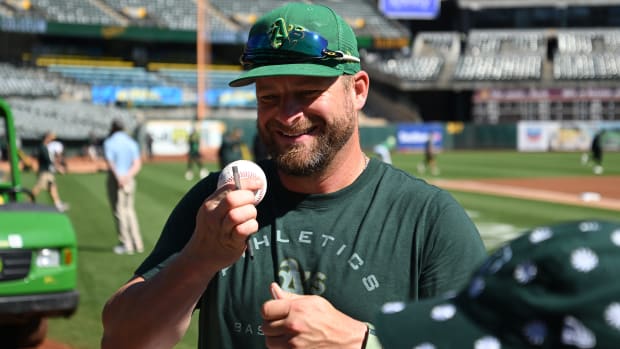 Stephen Vogt holds a baseball and a pen signing autographs