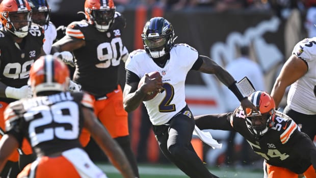 Tyler Huntley runs with the ball as multiple Browns defenders reach to tackle him