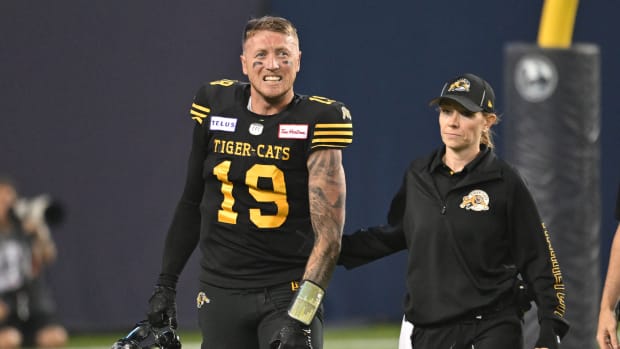 Jun 18, 2023; Toronto, Ontario, CAN; Hamilton Tiger-Cats quarterback Bo Levi Mitchell (19) is escorted off the field by team head therapist Claire Tofflemire after suffering an injury against the Toronto Argonauts in the fourth quarter at BMO Field. Mandatory Credit: Dan Hamilton-USA TODAY Sports