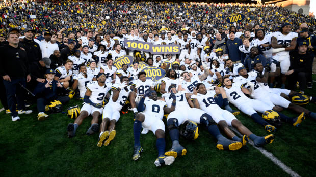 Michigan football players pose for photographers after winning the 1,000th game in program history.