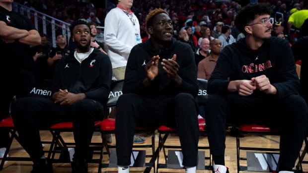 Cincinnati Bearcats forward Jamille Reynolds (13), center, sits with Cincinnati Bearcats forward Aziz Bandaogo (55), left, and Cincinnati Bearcats forward Sage Tolentino (44), right, in the second half of the NCAA basketball game between the Cincinnati Bearcats and the Northern Kentucky Norse at Fifth Third Arena in Cincinnati on Sunday, Nov. 19, 2023.