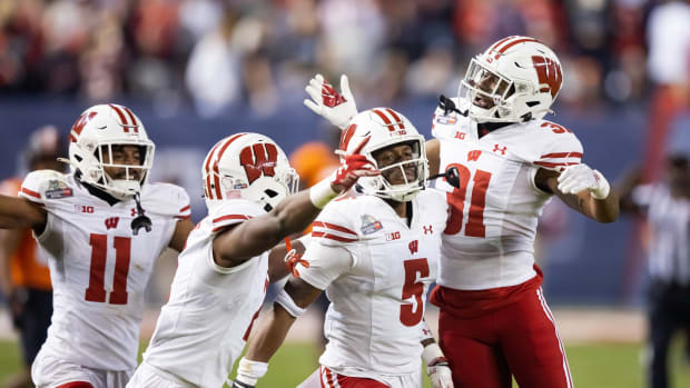 Dec 27, 2022; Phoenix, Arizona, USA; Wisconsin Badgers cornerback Cedrick Dort Jr. (5) celebrates with teammates after intercepting a pass against the Oklahoma State Cowboys in the second half of the 2022 Guaranteed Rate Bowl at Chase Field. Mandatory Credit: Mark J. Rebilas-USA TODAY Sports