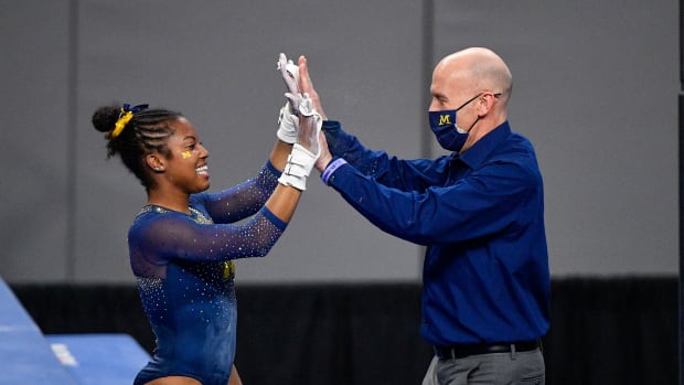 Apr 16, 2021; Fort Worth, Texas, USA; University of Michigan Wolverines gymnast Sierra Brooks and assistant coach Scott Sherman during the 2021 NCAA Women Gymnastics Championships at Dickies Arena