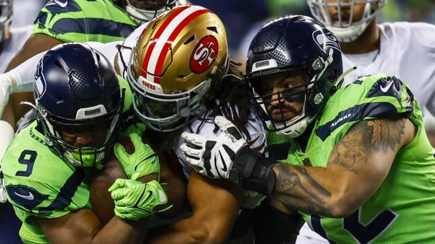 San Francisco 49ers linebacker Fred Warner (54) tackles Seattle Seahawks running back Kenneth Walker III (9) as offensive tackle Abraham Lucas (72) blocks during the second quarter at Lumen Field.