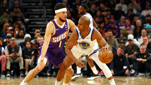 Golden State Warriors guard Chris Paul (3) handles the ball against Phoenix Suns guard Devin Booker (1) during the first quarter at Footprint Center.