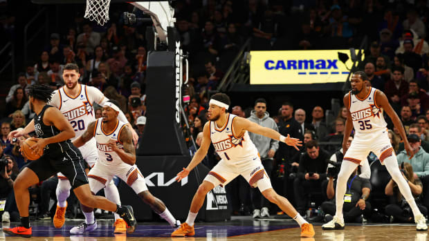 Bradley Beal defends a player with the ball as Devin Booker and Kevin Durant prepare to crash next to him