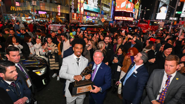 Dec 9, 2023; New York, New York, USA; Heisman Trophy winner Jayden Daniels poses with LSU coach Brian Kelly with the trophy in Times Square.