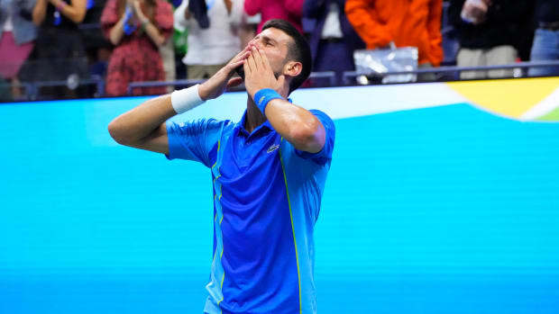 Novak Djokovic puts two hands to his mouth to blow a kiss to the audience