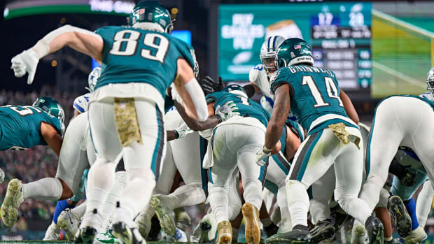 Eagles players rush forward to push quarterback Jalen hurts over the cowboys’ defense