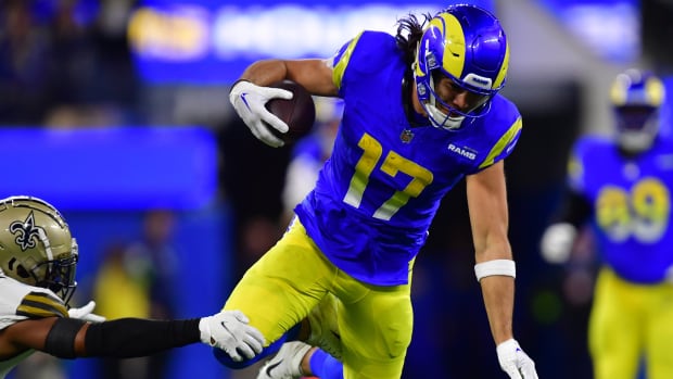 Los Angeles Rams wide receiver Puka Nacua leaps to avoid a tackle while carrying the football.