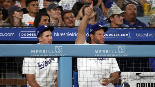 Walker Buehler and Clayton Kershaw watch a game from the dugout.