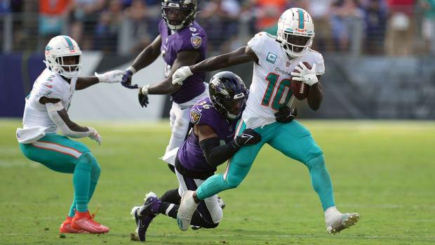 Tyreek Hill runs after the catch in a Dolphins game against the Ravens while he is tackled from behind