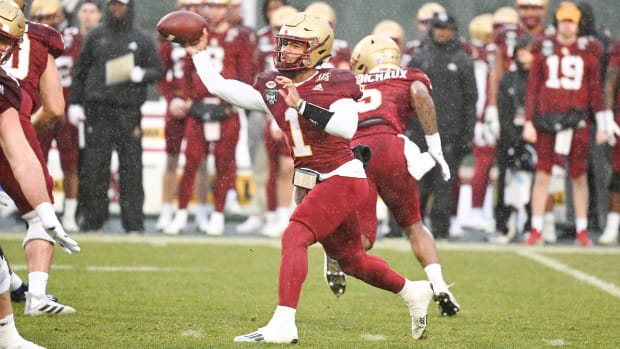 Boston College's quarterback throws a pass in the rain at the Fenway Bowl