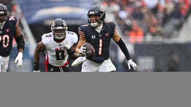 Dec 31, 2023; Chicago, Illinois, USA; Chicago Bears quarterback Justin Fields (1) scrambles away from outside linebacker Lorenzo Carter (0) for yards in the first half against the Atlanta Falcons at Soldier Field.