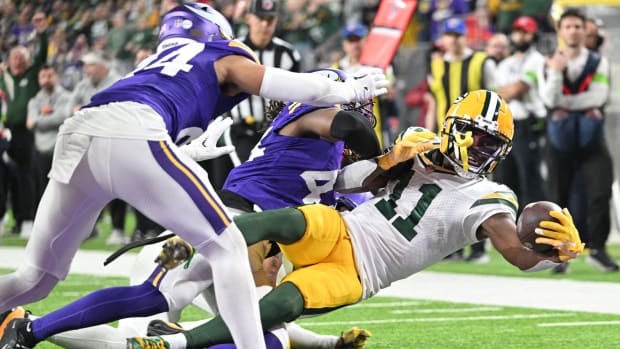Dec 31, 2023; Minneapolis, Minnesota, USA; Green Bay Packers wide receiver Jayden Reed (11) scores a touchdown as Minnesota Vikings safety Josh Metellus and safety Camryn Bynum (24) attempt to make the tackle during the second quarter at U.S. Bank Stadium.