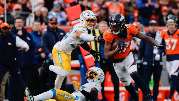 Denver Broncos wide receiver Lil'Jordan Humphrey (17) runs through the tackle of Los Angeles Chargers safety Alohi Gilman (32) and cornerback Essang Bassey (27) in the second quarter at Empower Field at Mile High.