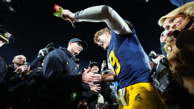 Michigan quarterback J.J. McCarthy and head coach Jim Harbaugh embrace on the field after winning the Rose Bowl.