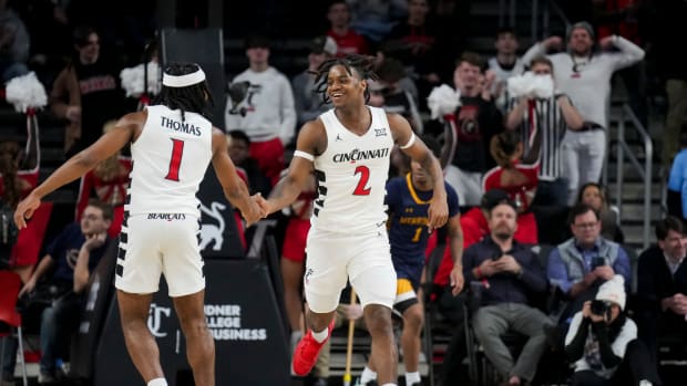 Dec 19, 2023; Cincinnati, Ohio, USA; Cincinnati Bearcats guard Jizzle James (2) high-fives guard Day Day Thomas (1) after a play against the Merrimack Warriors in the second half at Fifth Third Arena. Mandatory Credit: Aaron Doster-USA TODAY Sports