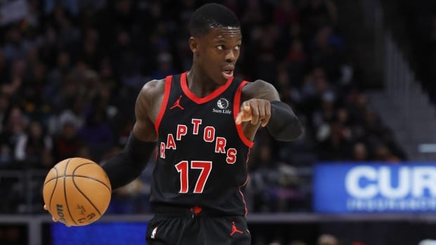 Toronto Raptors point guard Dennis Schröder signals a play while dribbling a ball during a game.