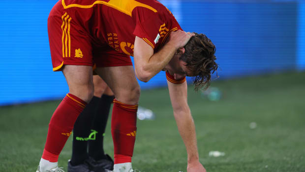 Roma defender Edoardo Bove pictured holding the back of his neck after being struck by a beer bottle thrown from the crowd during a game against Lazio in January 2024