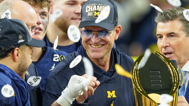 Confetti falls on Jim Harbaugh as he holds the national championship trophy after the title game.